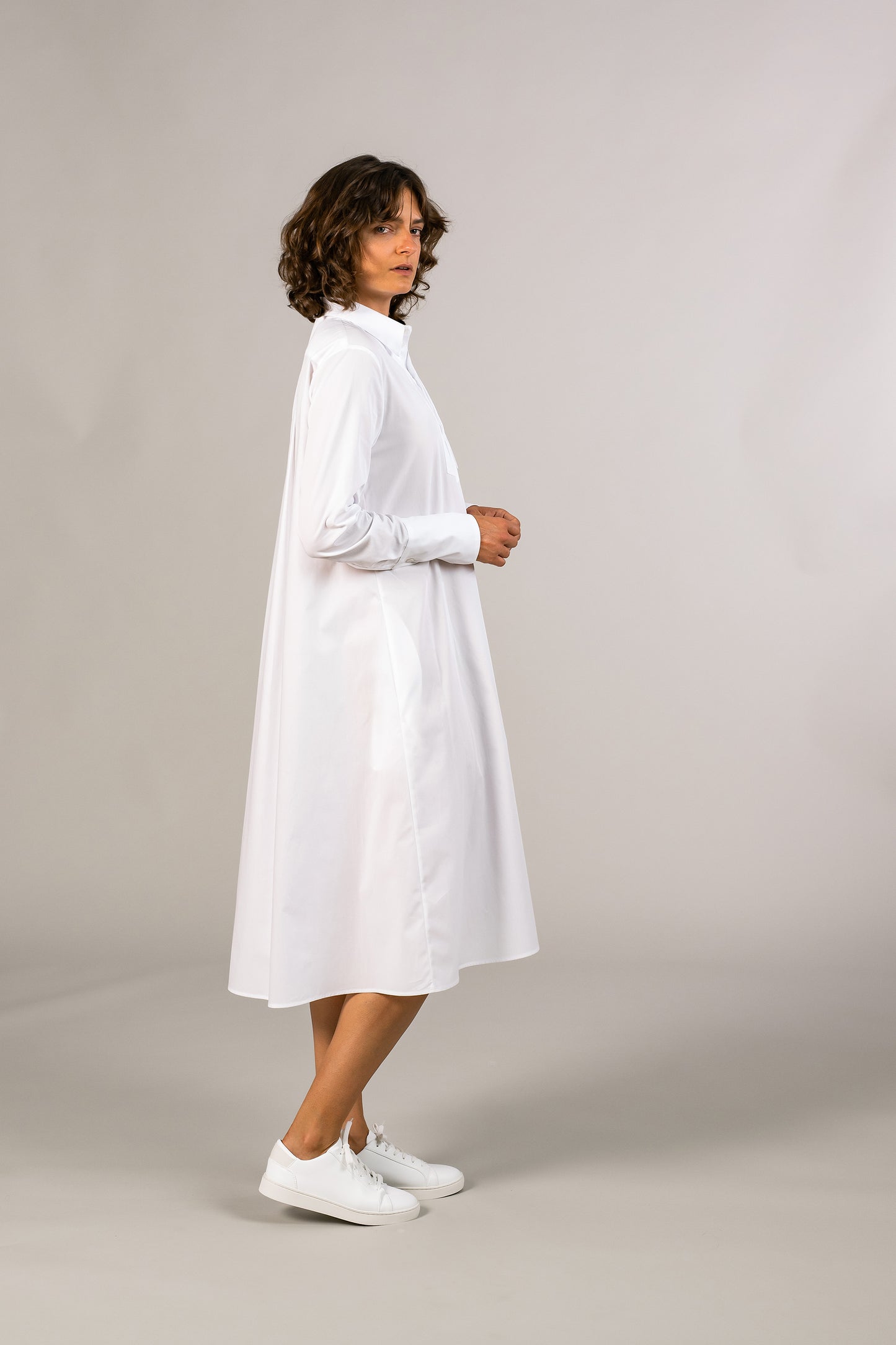 Side view of womens white tuxedo shirt dress, 100% sustainable cotton poplin from Italy, long sleeve, button down knee length.