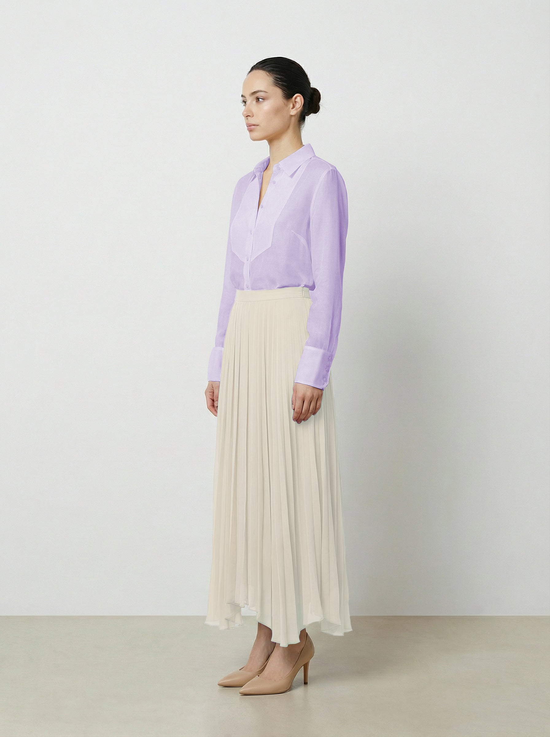 Woman wearing a light purple  translucent organza blouse and creme pleated skirt on a white background