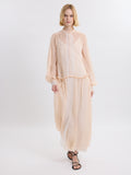 Model wearing a pink chiffon dress  with lace details on a white background