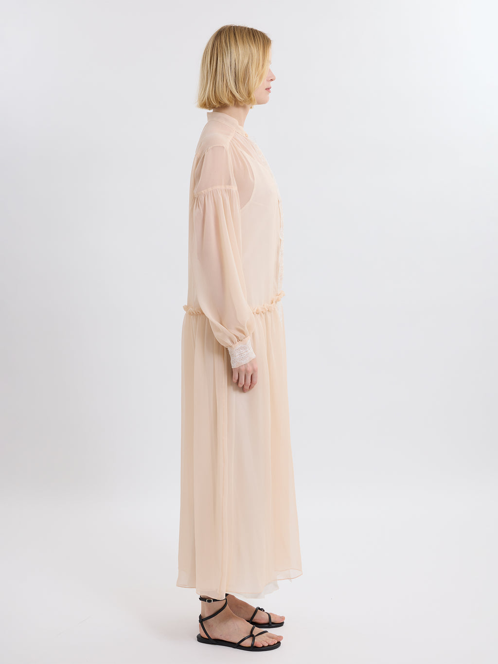 Woman wearing a long pink chiffon dress on a white background