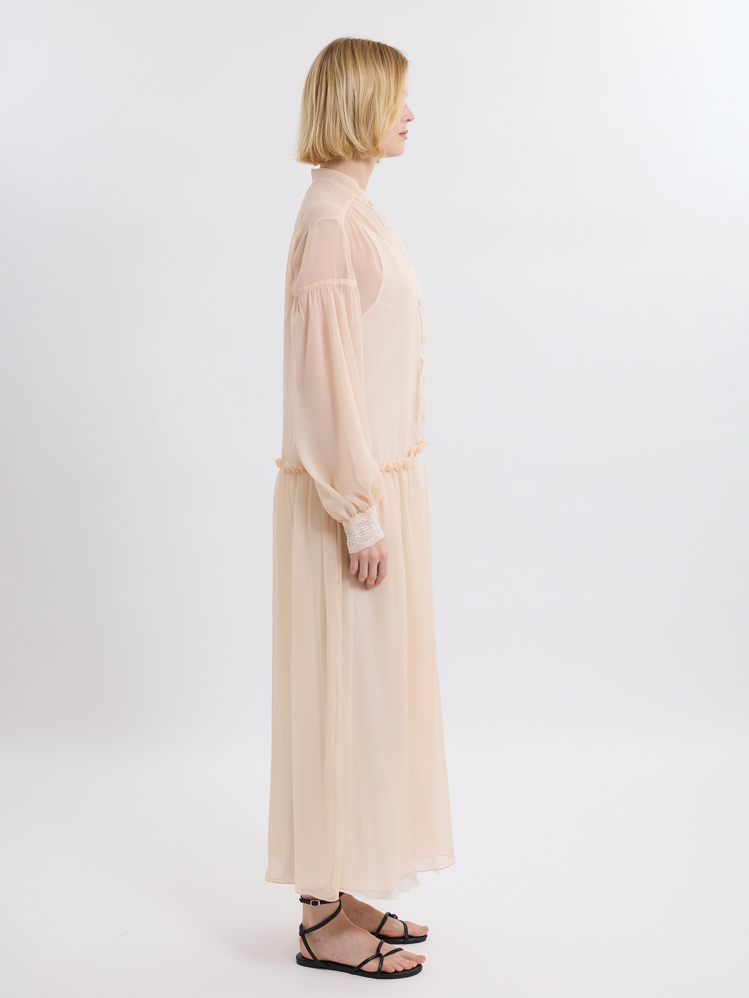 Woman wearing a long pink chiffon dress on a white background
