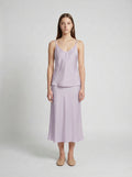 Woman wearing a light purple  camisole top and half slip on a white background
