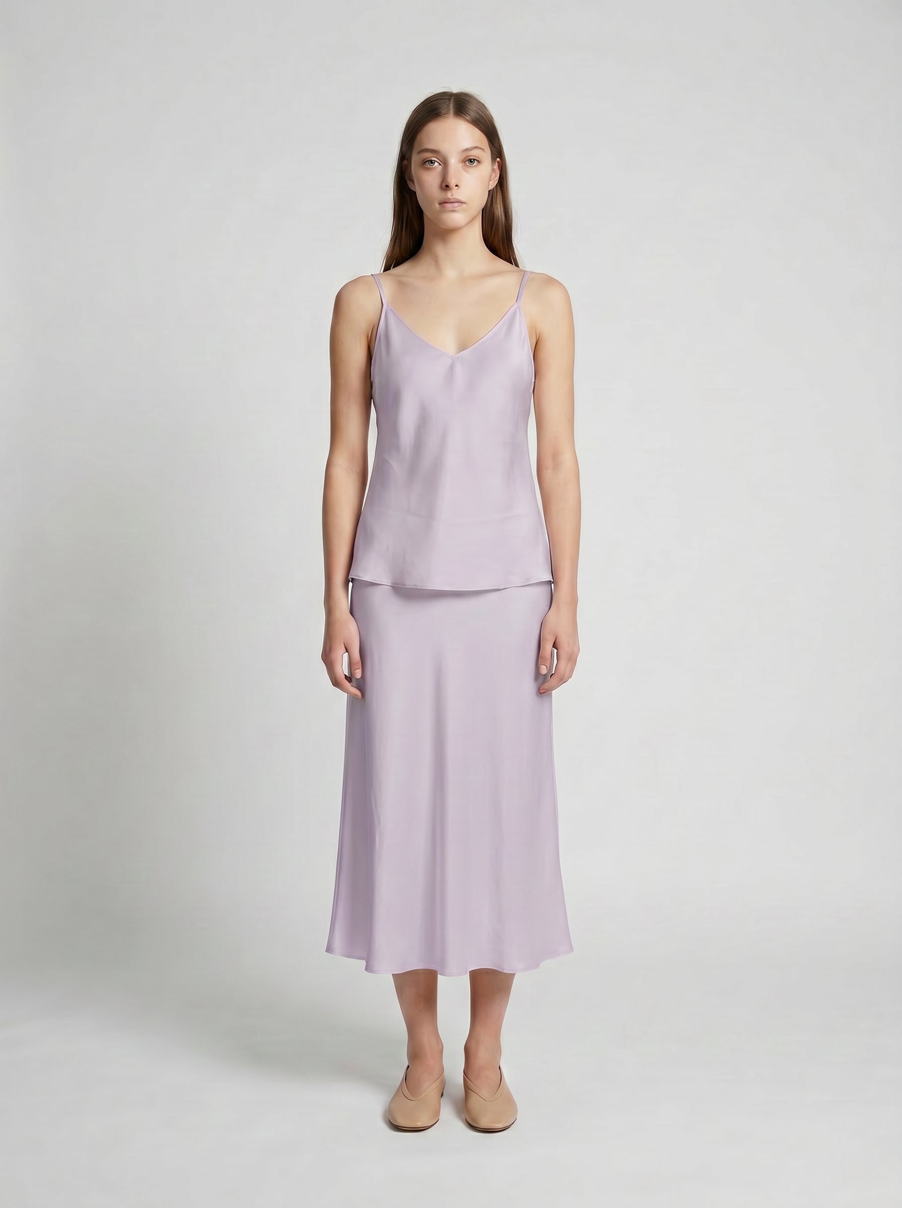 Woman wearing a light purple  camisole top and half slip on a white background