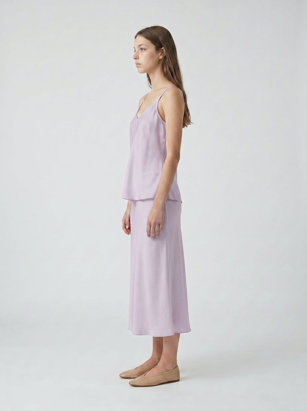 Woman wearing a light purple silk slip top and half slip skirt on a white background