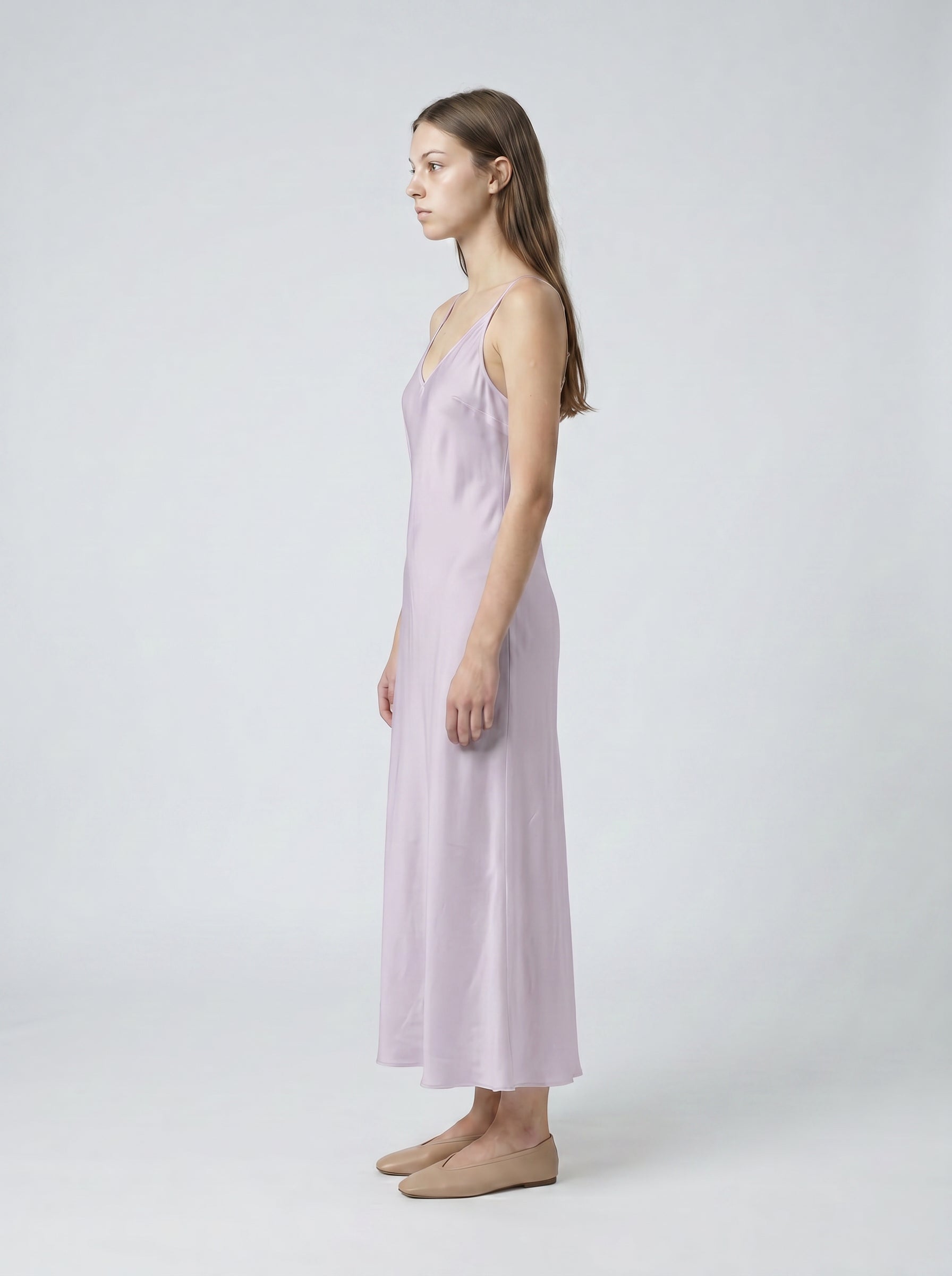 Woman wearing a light purple slip dress on a white background 