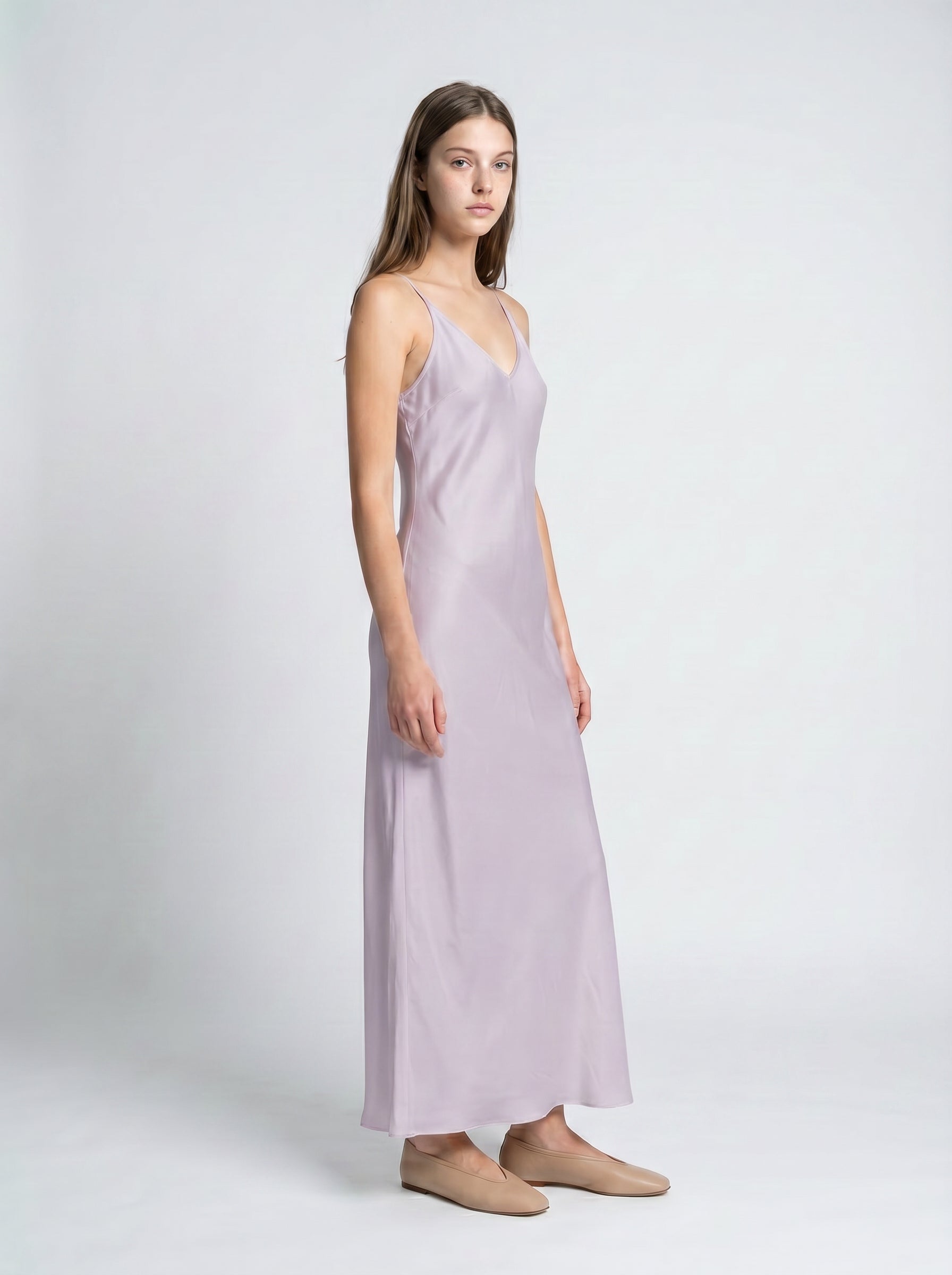 Woman wearing a light purple slip dress on a white background 