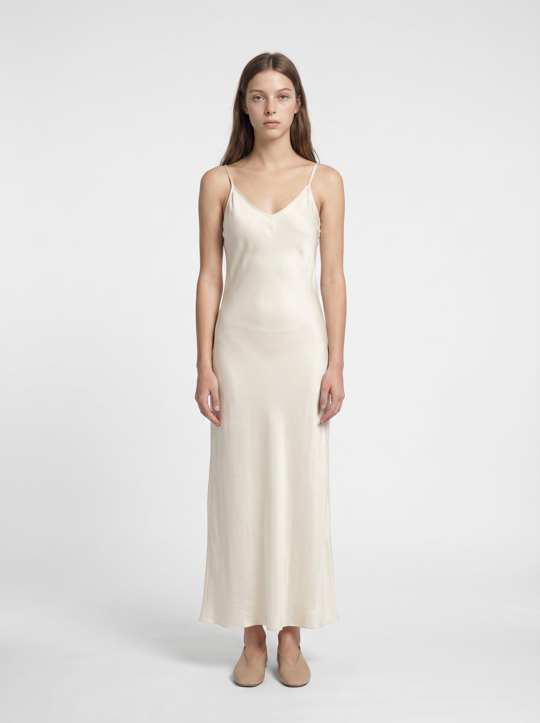 Woman wearing a white slip dress on a white background