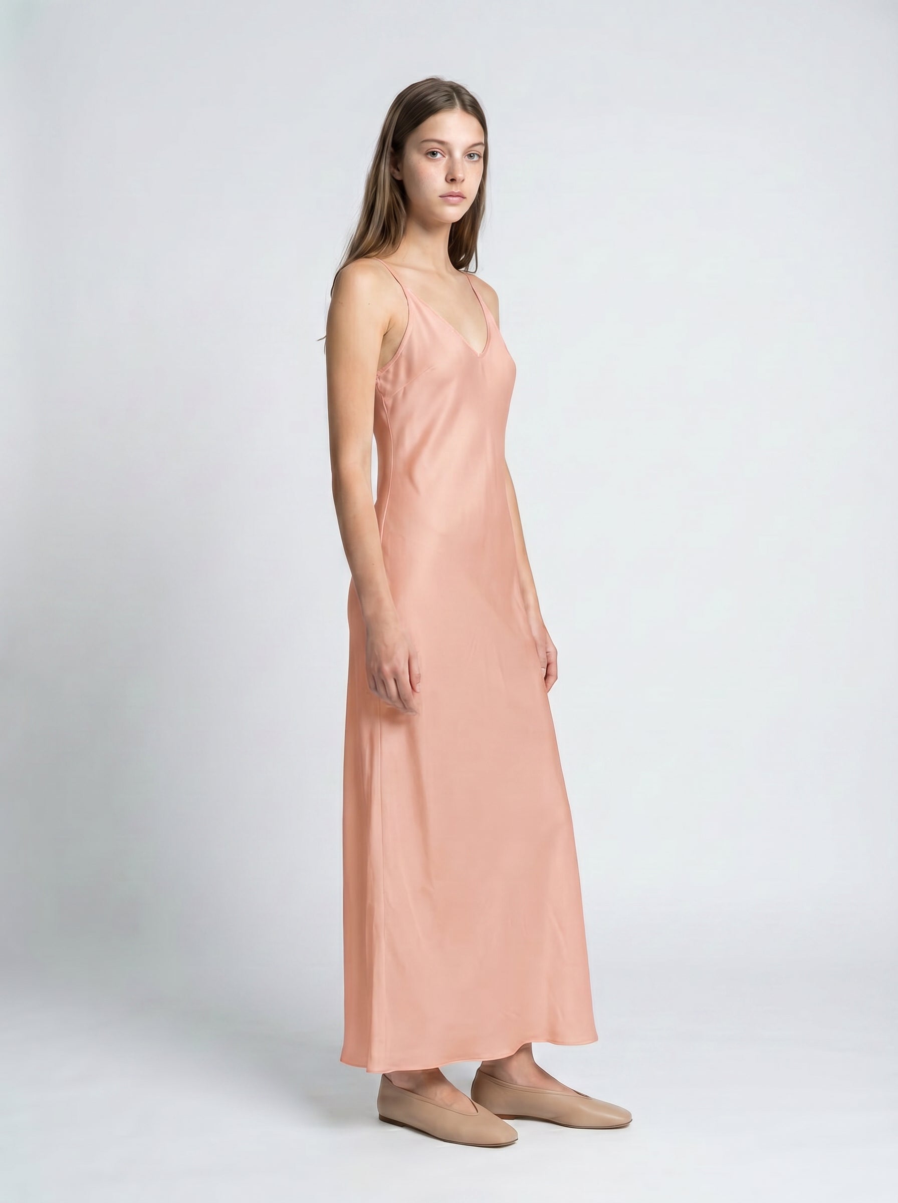 Woman wearing a pink slip dress on a white background