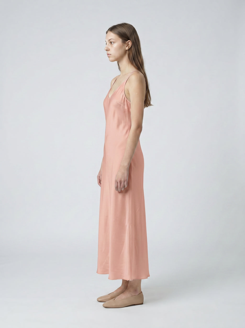 Woman wearing a pink slip dress on a white background