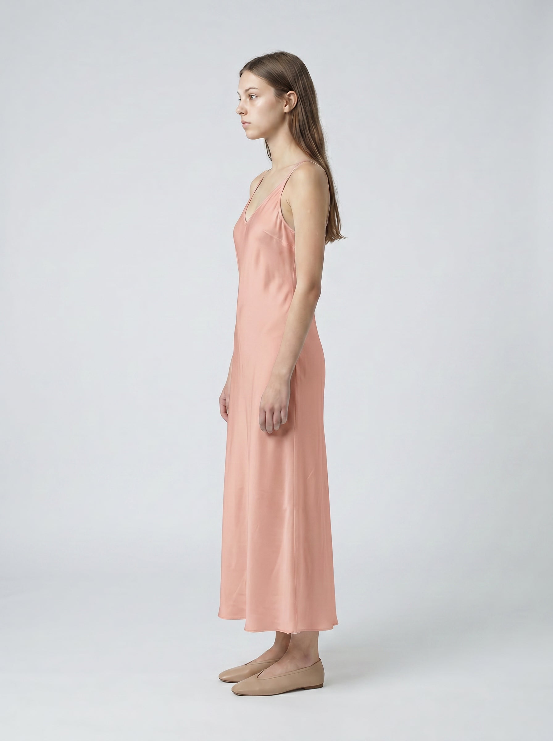 Woman wearing a pink slip dress on a white background