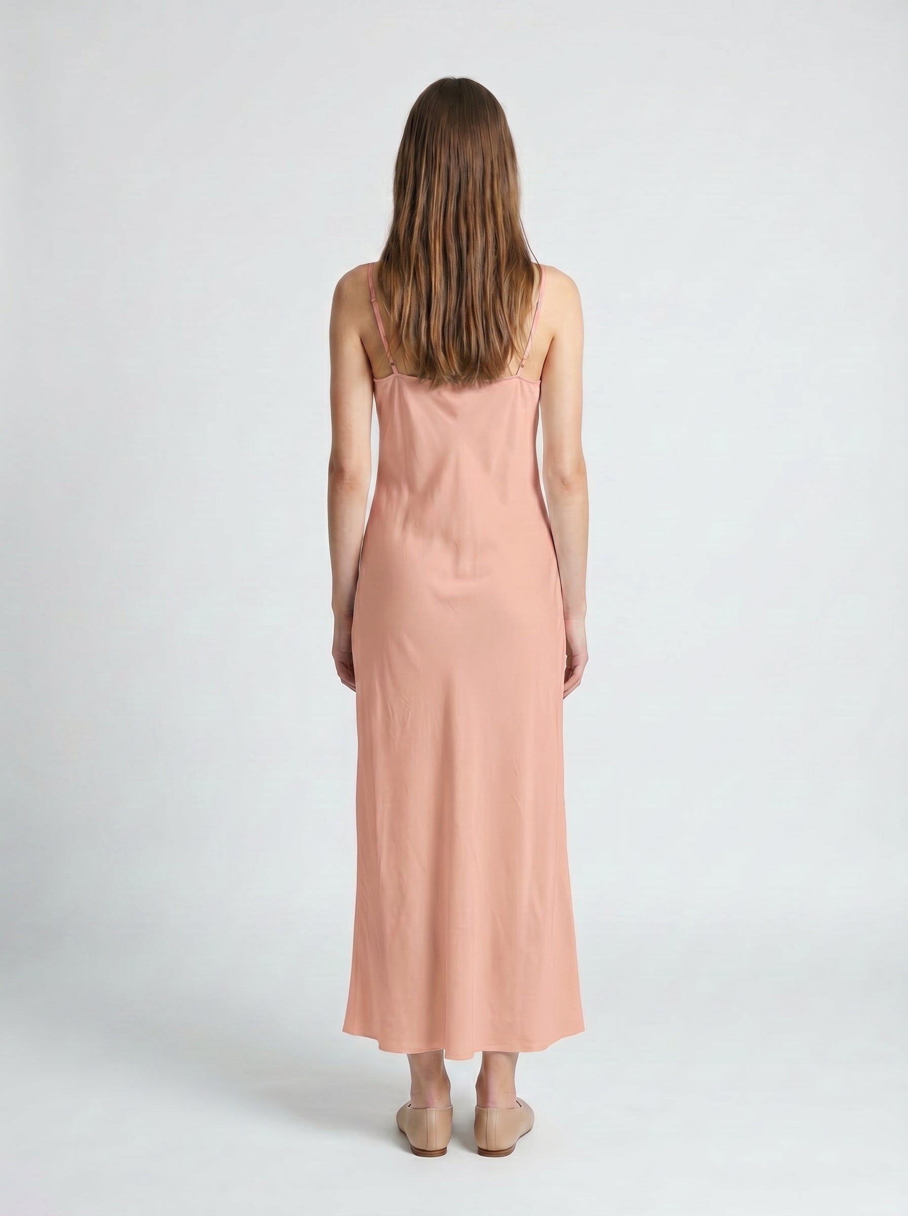 Woman wearing a pink dress from behind on a white background