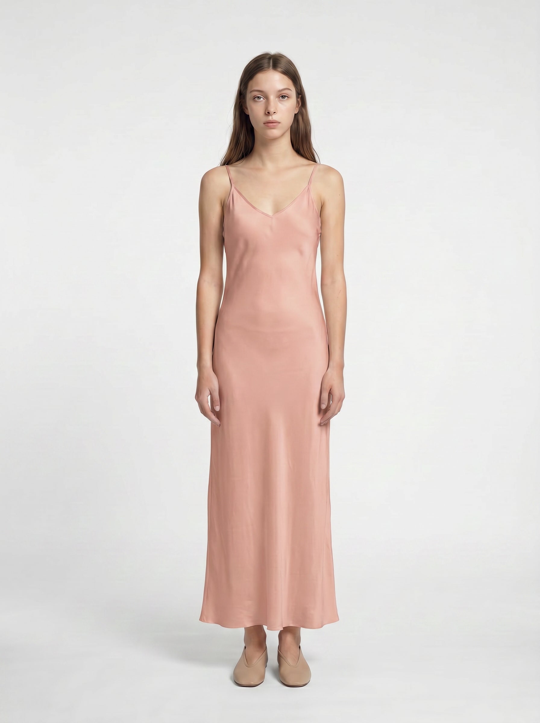 Woman wearing a pink slip dress on a white background