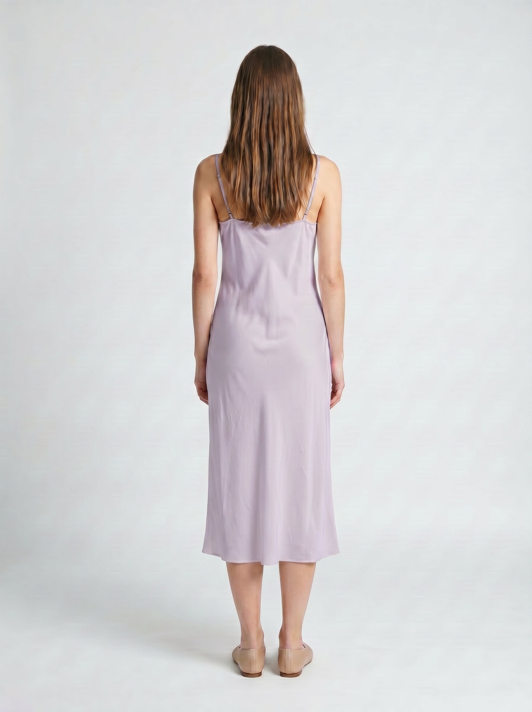 Woman wearing a light purple slip dress against a white background