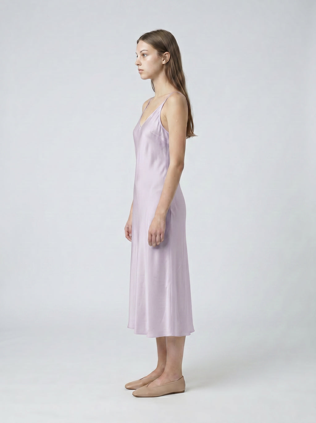 Woman wearing a light purple slip dress on a white background
