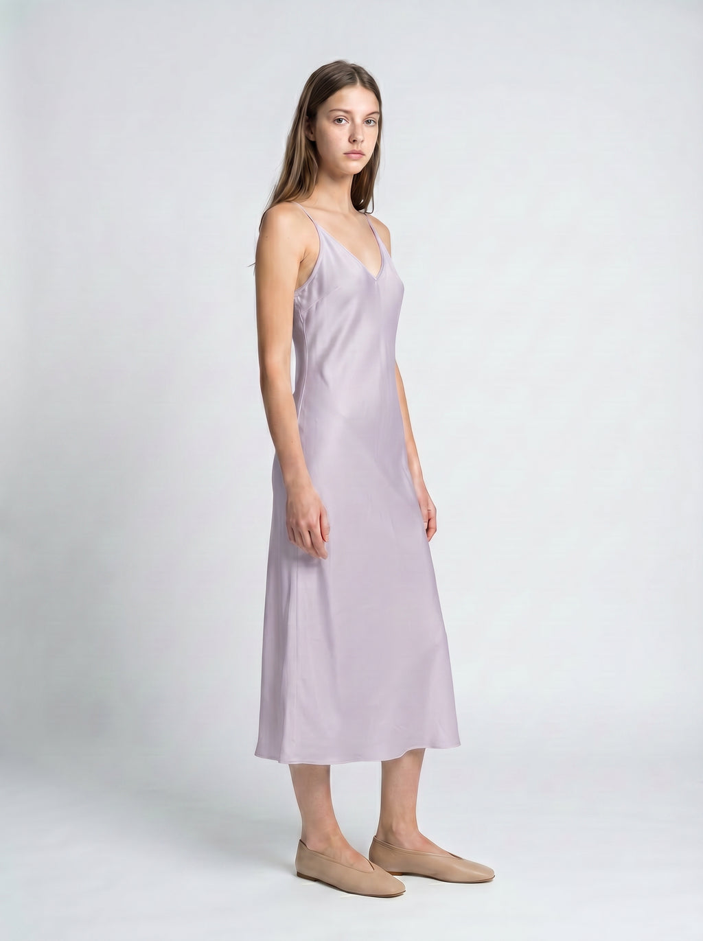 Woman wearing a light purple slip dress on a white background