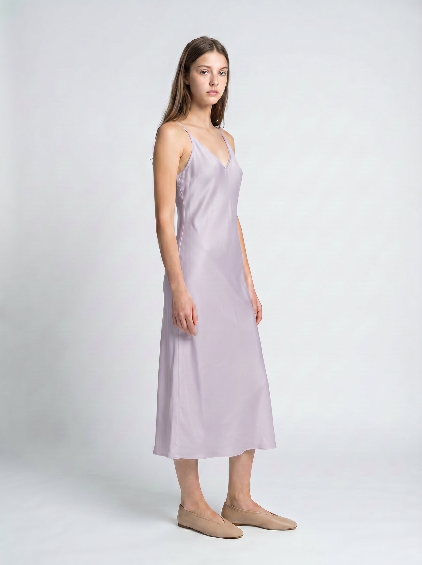 Woman wearing a light purple slip dress on a white background