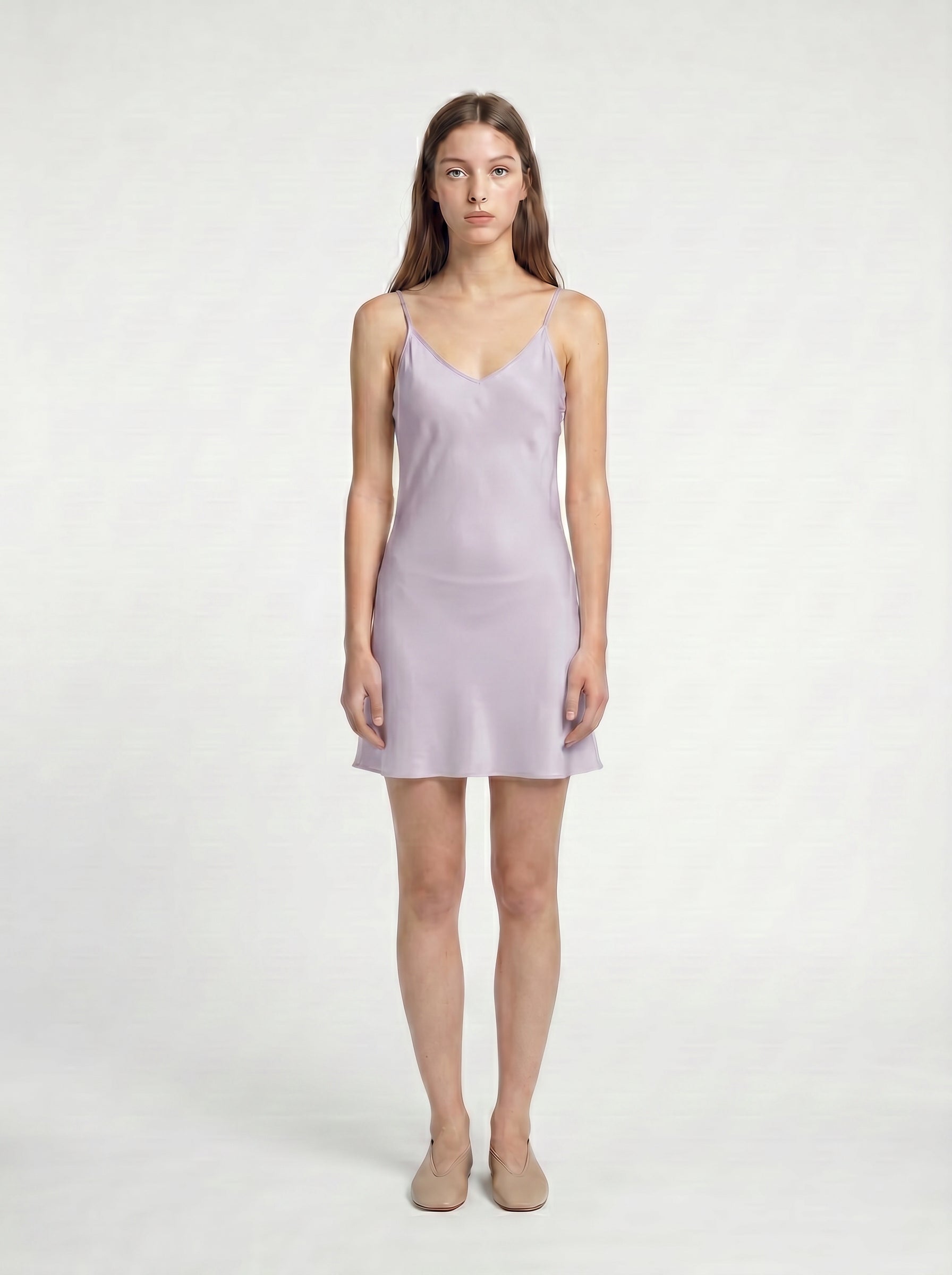 Woman wearing a light purple  mini slip dress on a white background 