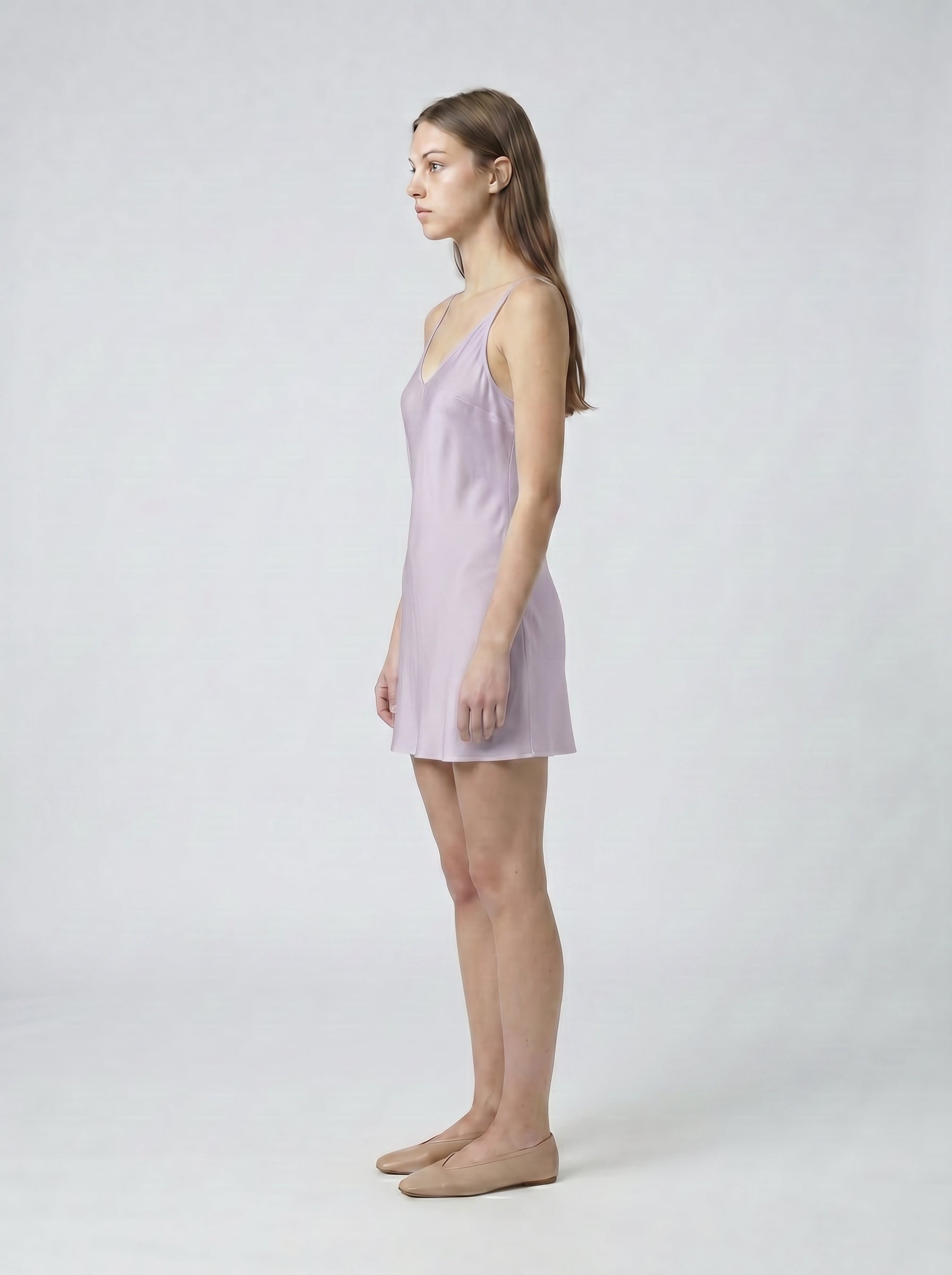 Woman wearing a light purple slip dress against a white background 