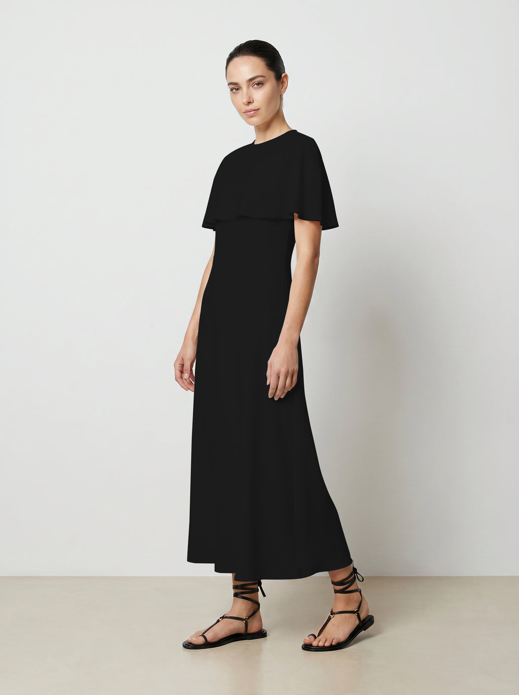 Woman wearing a black dress against a plain background 3/4 view
