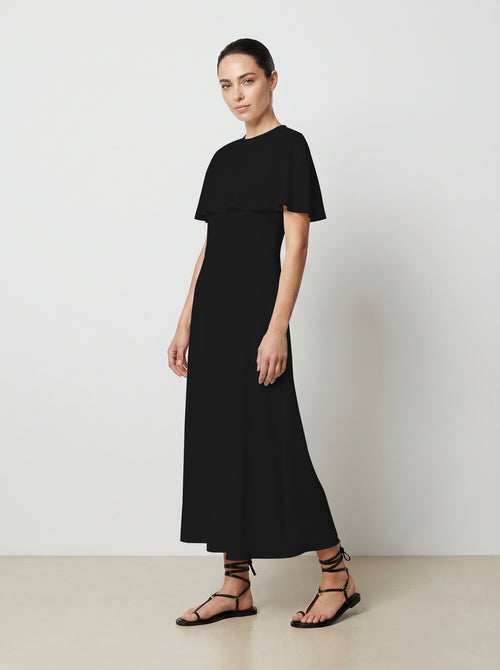 Woman wearing a black dress against a plain background 3/4 view