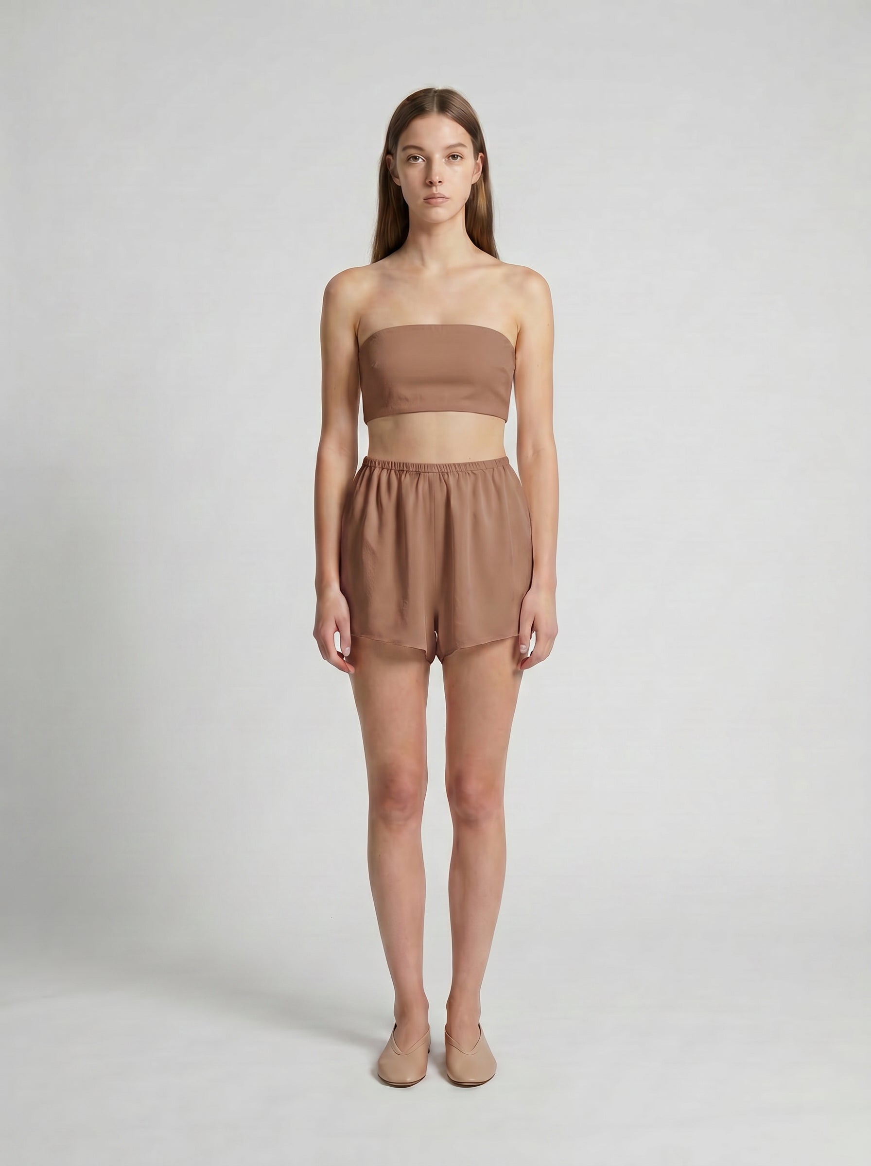 Woman wearing a brown strapless top and shorts set on a white background