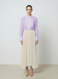 Woman wearing a light purple  translucent organza blouse and creme pleated skirt on a white background