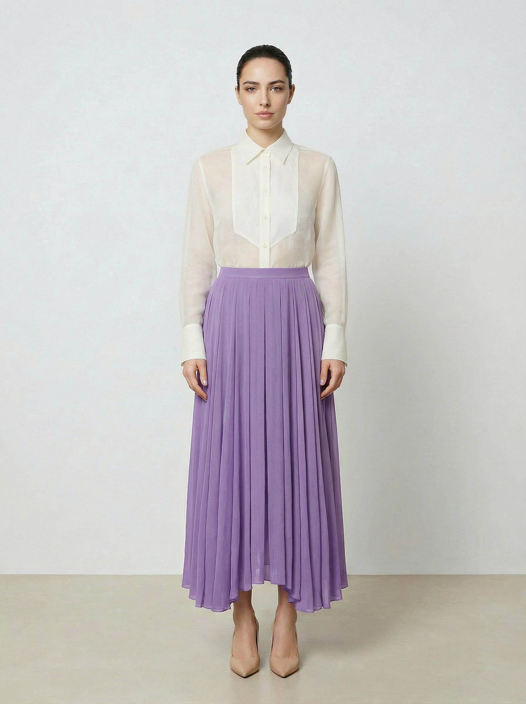 Woman wearing a creme colored  organza blouse and purple skirt on a plain background