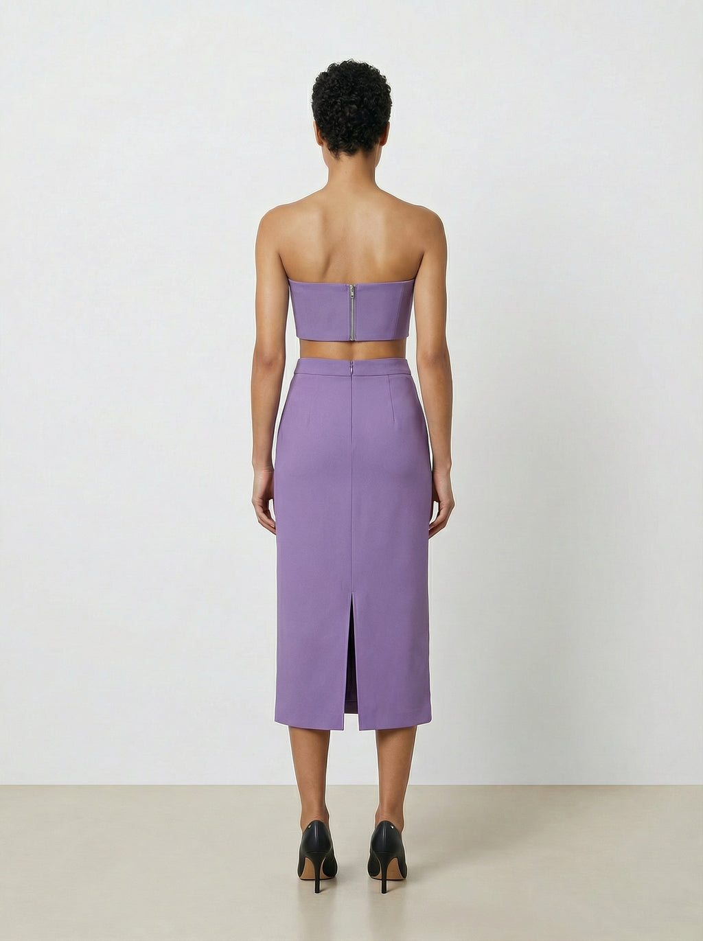 Woman wearing a purple strapless top and skirt set on a white background