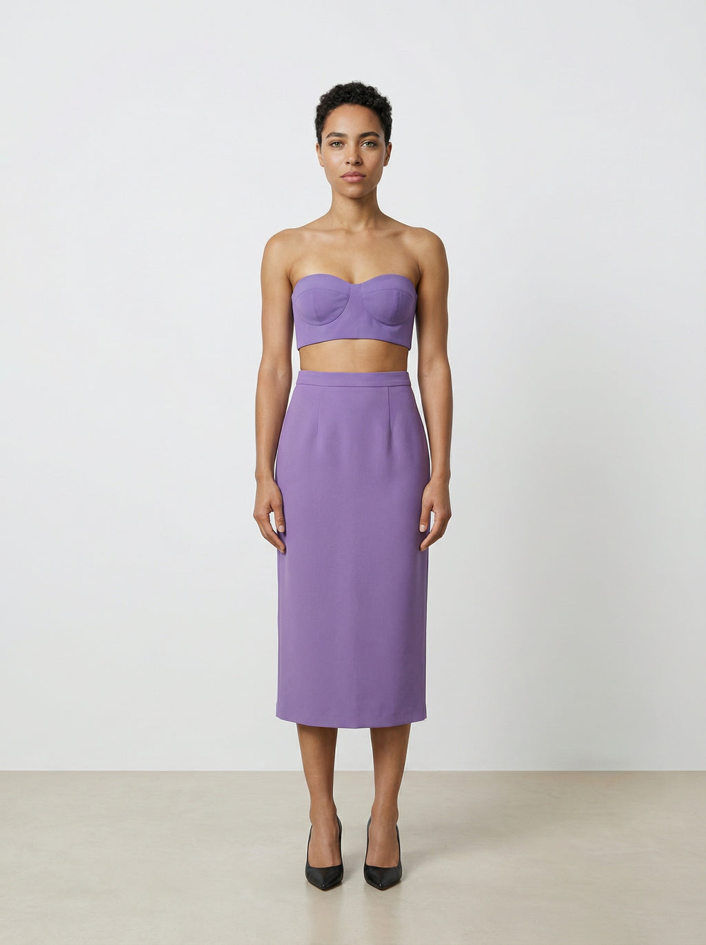 Woman wearing a purple strapless top and skirt set on a white background