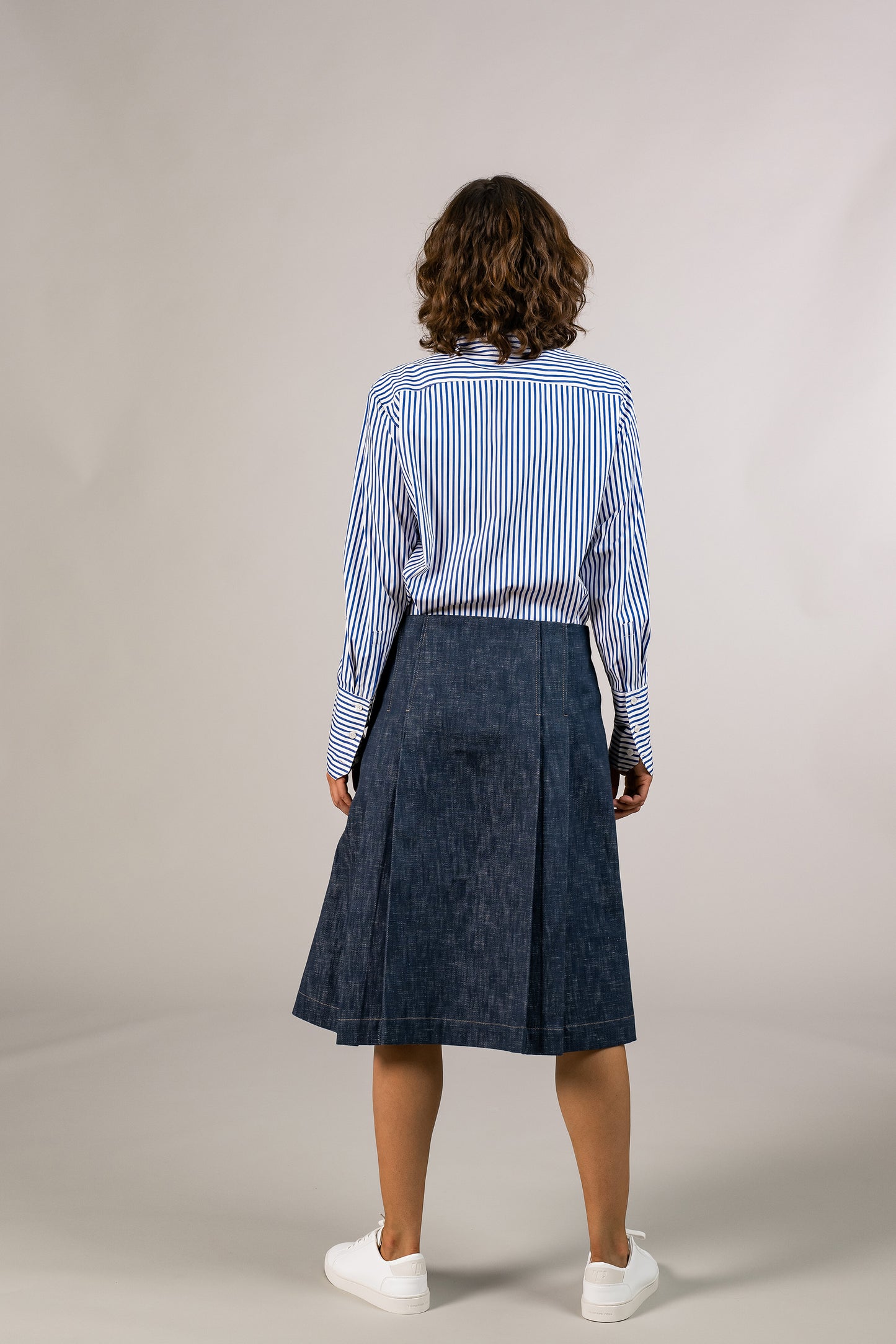 Back view of womens knee high pleated wrap skirt, made with sustainable 100% cotton dark denim, hooked on side. Made in America.