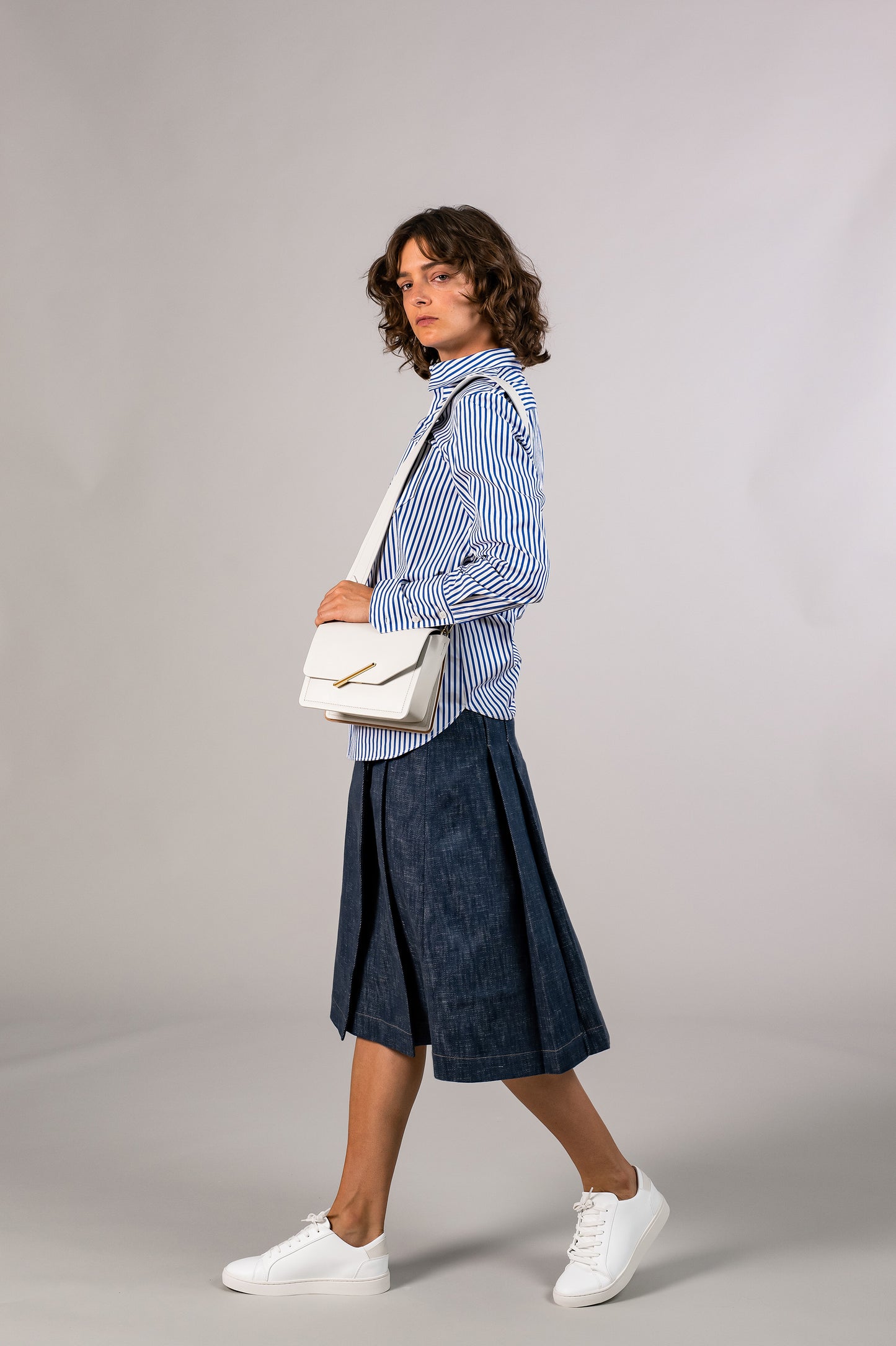 Side view of womens knee high pleated wrap skirt, made with sustainable 100% cotton dark denim, hooked on side. Made in America.