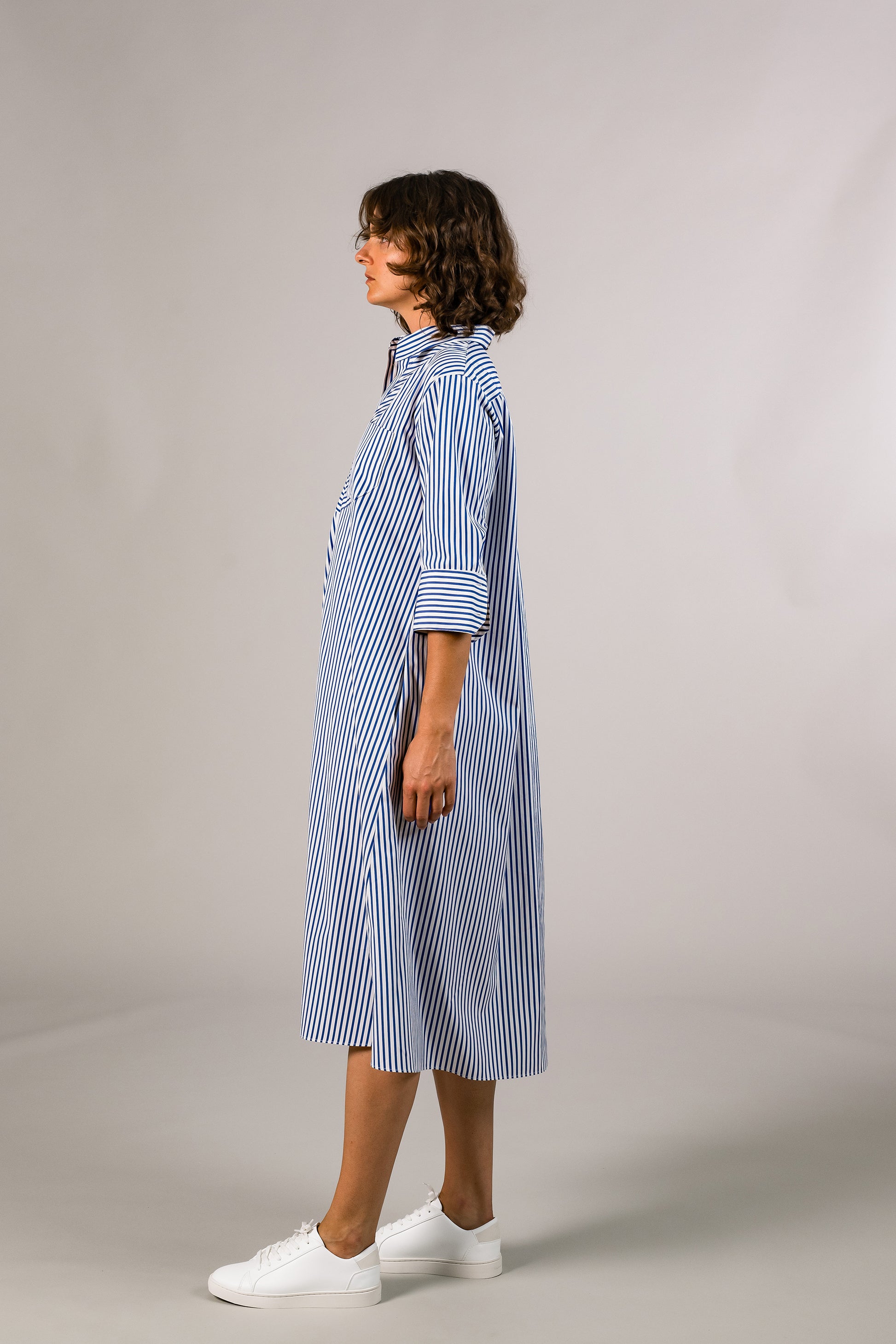 Profile view of half sleeve blue stripe shirt dress, 100% cotton poplin from Italy, knee length button down. Made in America.